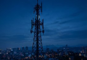 Torre de telecomunicaciones sobre la ciudad al anochecer