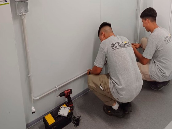 Dos técnicos de RC Sistemas colocando la cañería de una instalación sobre el zócalo de una pared